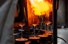 Load image into Gallery viewer, Creating wave-effect Amphitrite champagne flutes in a glassblowing process with molten glass and intricate artistry.